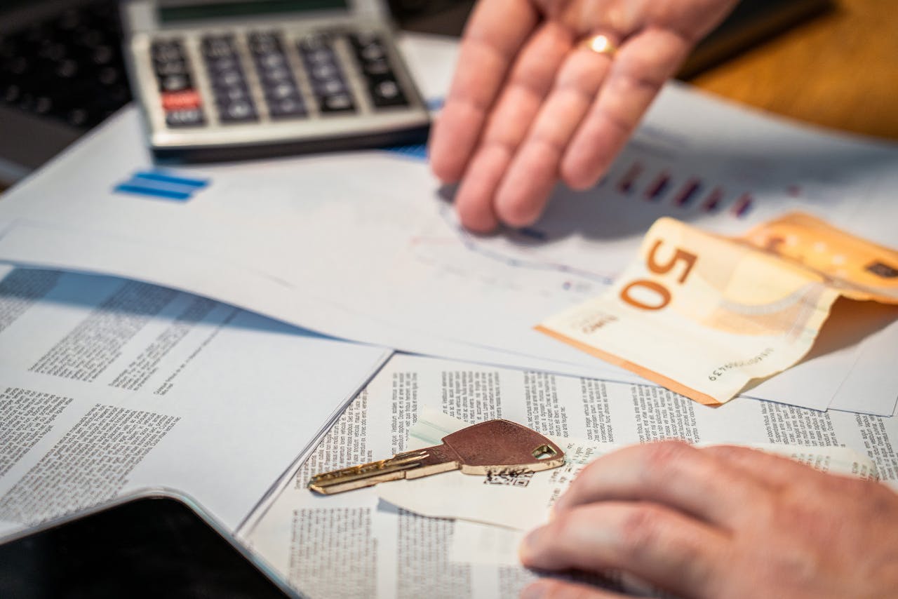 about-01 Hands examining financial documents, a 50 euro note, and a key, suggesting investment or real estate themes.